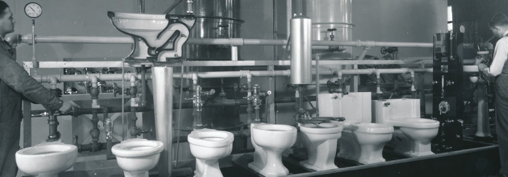 Two men working on a line of toilets