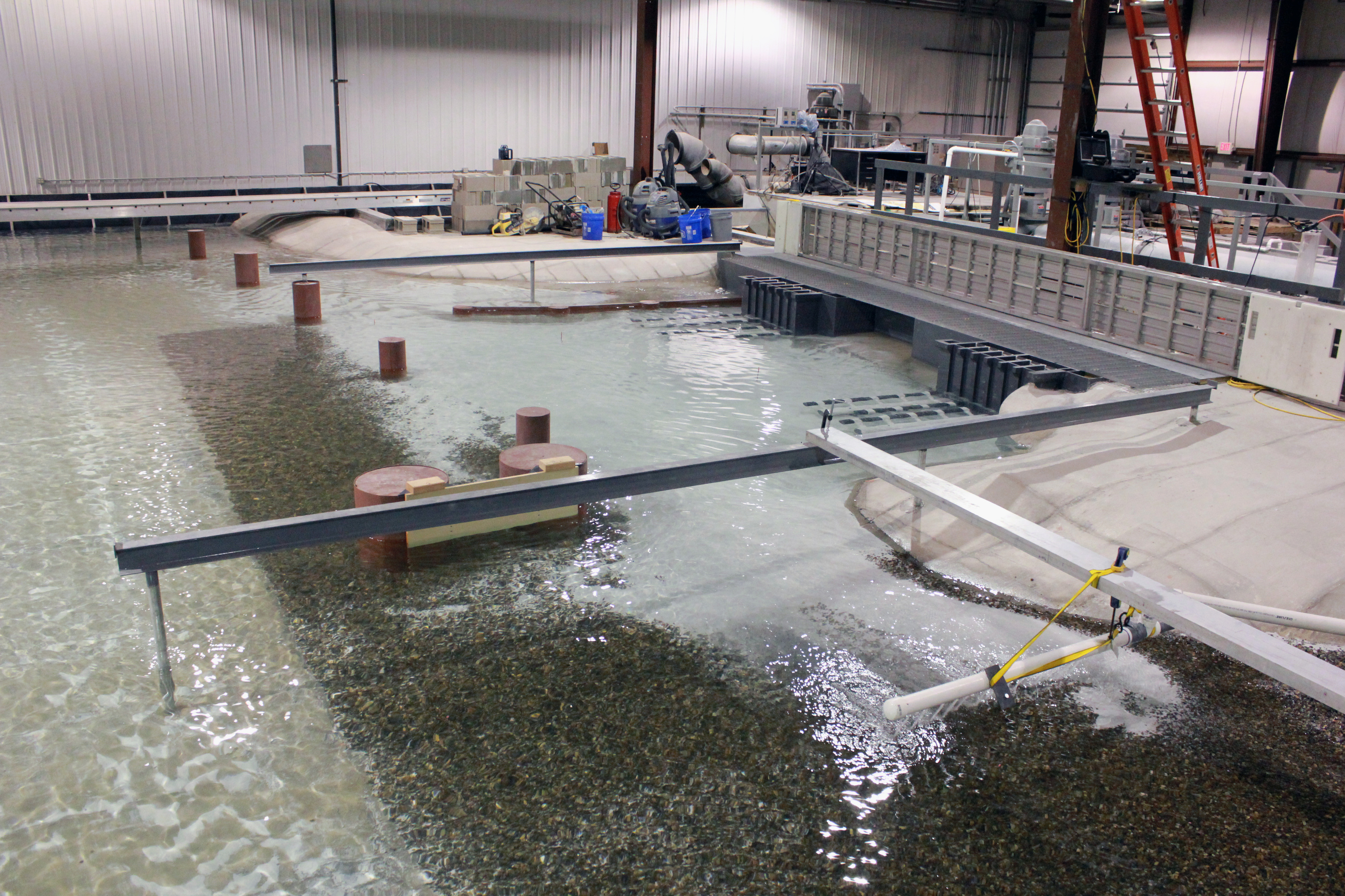 A warehouse with a large physical engineering model in it, filled with water. 
