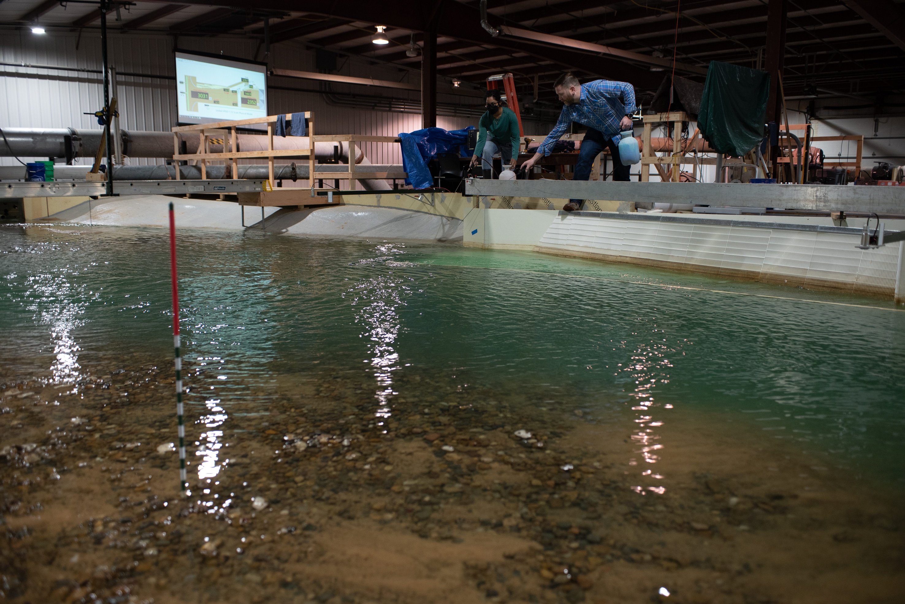 Workers on the side of the model, in the process of adding dye to view flow dynamics
