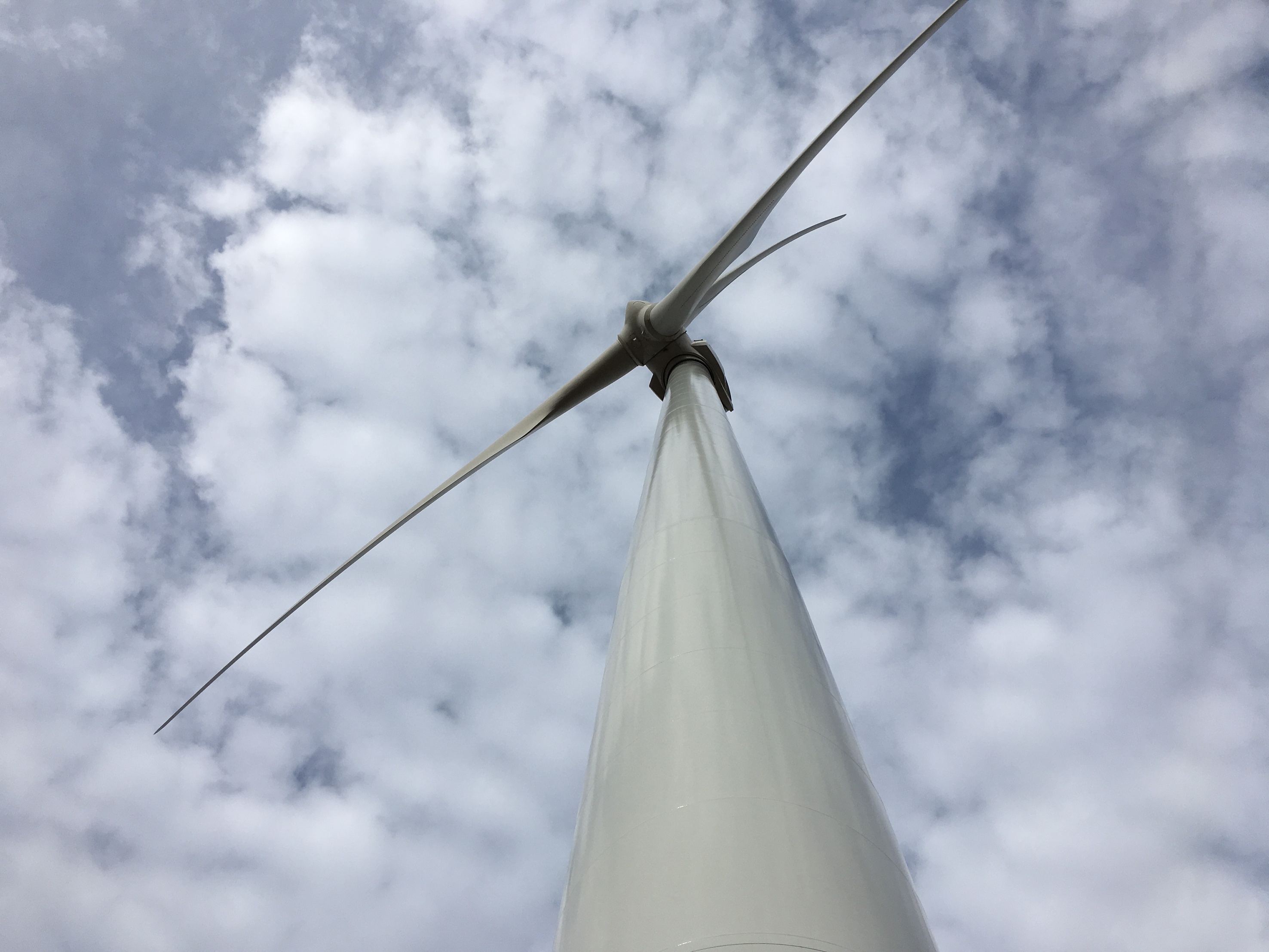 Looking up at a wind turbine against a greyish blue cloud filled sky
