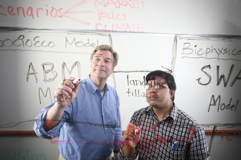 Jerry Schnoor writes on a board with a student