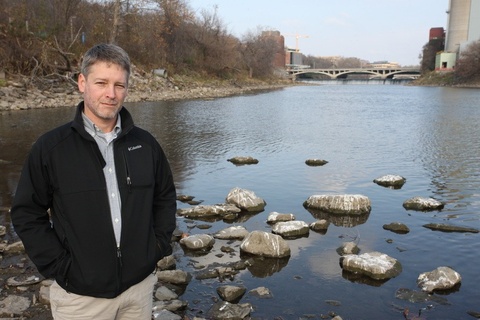 Tim Mattes poses for a photo by the Iowa River