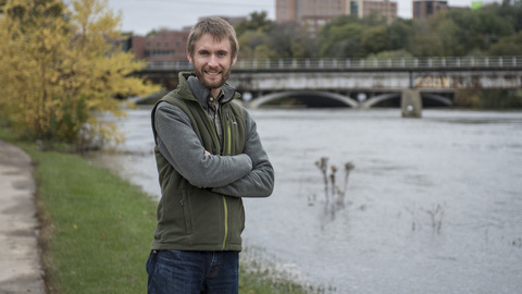 Gregory LeFevre poses for a photo by the Iowa River