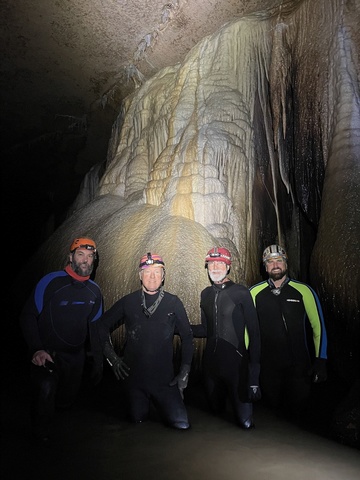 Four people wearing wetsuits in a cave