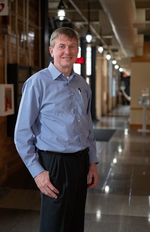Larry Weber poses for a photo in a hallway