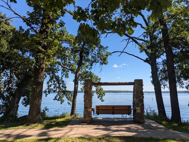 Gull Point at West Lake Okoboji with green leafy trees and blue water in the background
