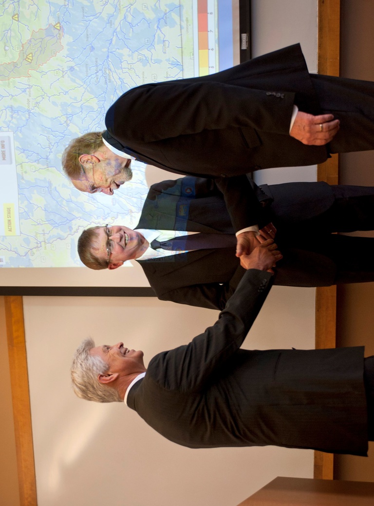 Two people shaking hands while another looks on