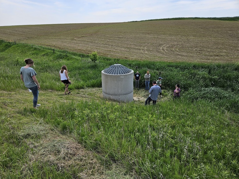 A group of people walking to an on road structure down a grassy hill