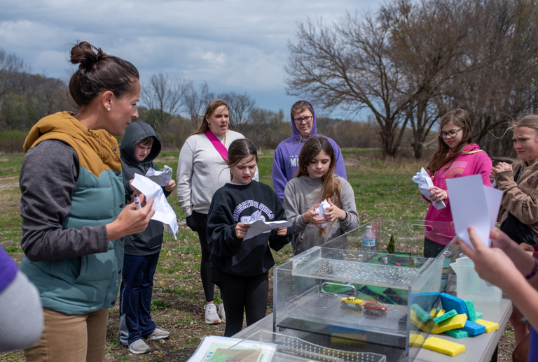 Breanna Shea discusses the watershed model with children surrounding