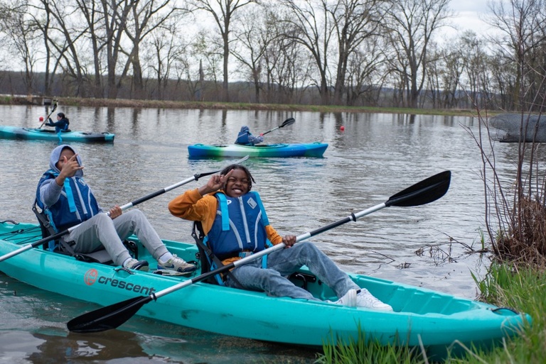 Kids paddle out in a blue kayak