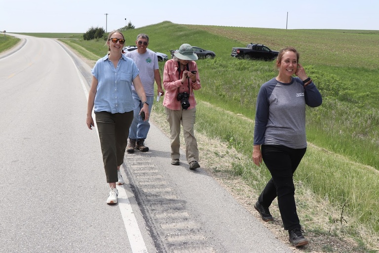 a few people walk along the side of a highway, chatting