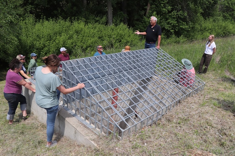 a group of people look at an on road structure on a hill