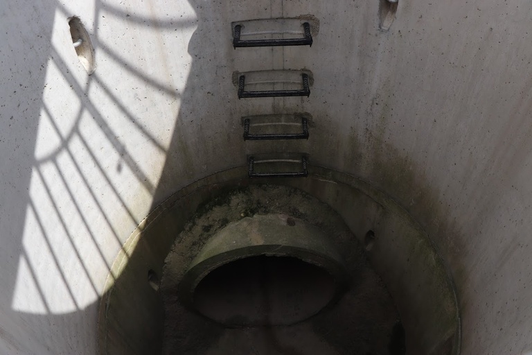 the inside of an on road structure, with shadows cast on the walls from the wire cover