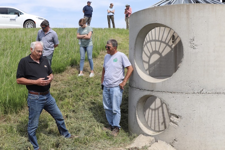 a few gathered people look inside the on road structure in the grass