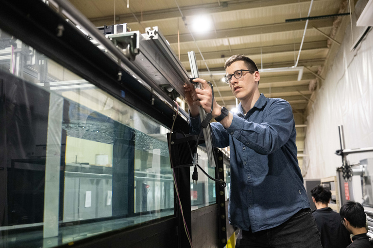 An IIHR student researcher sets up wiring along the flume for their experiments