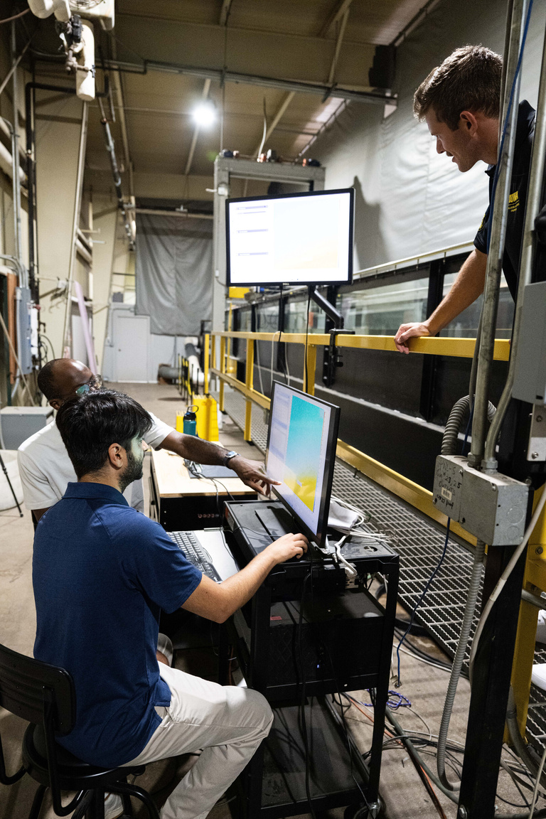 two researchers look at the computer model of their bridge pier model in the experimental flume