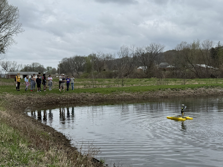 Students take turns operating a remote control drone boat