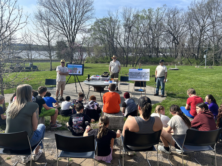 Students listen to a lecture on the history of the site along the Mississippi River
