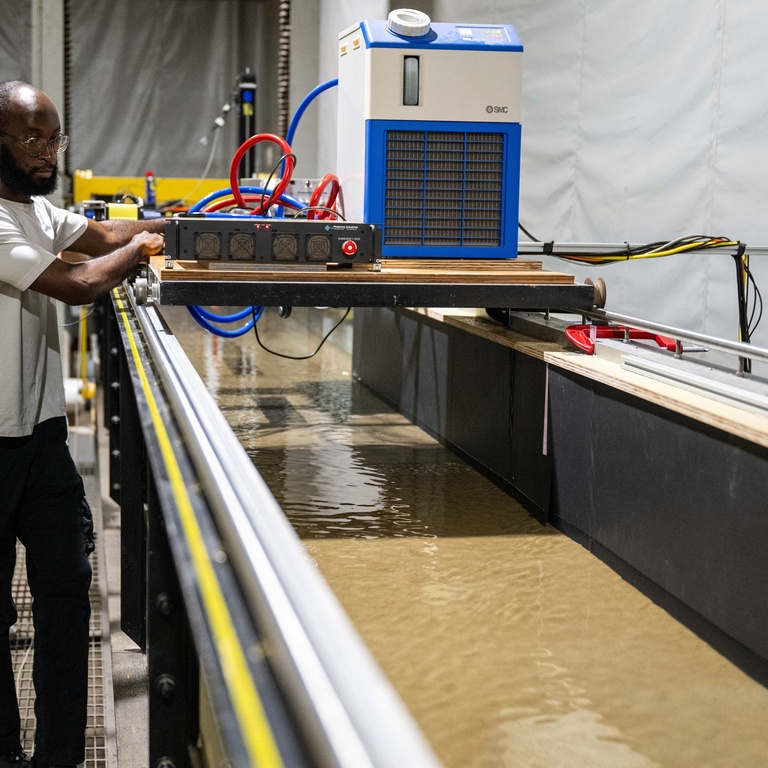 Chukwudum looks into the flume with sediment