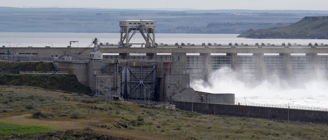 McNary Dam as water rushes through the output, against a grey sky