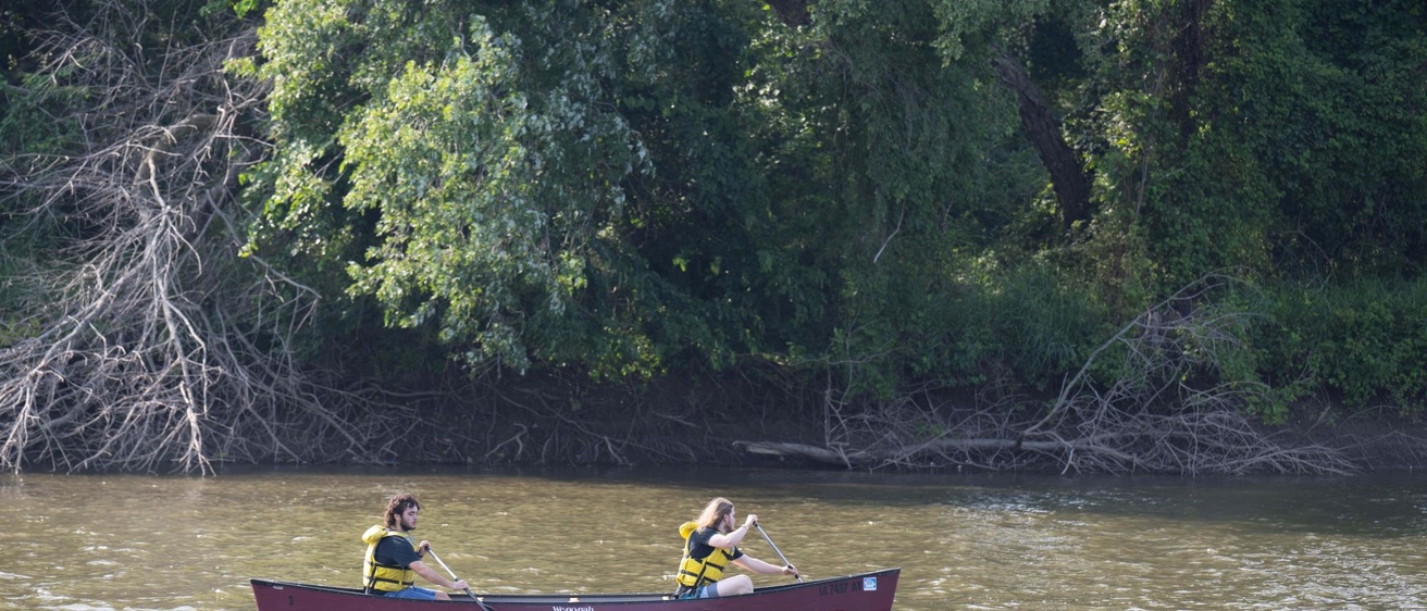 Two people in a canoe paddle down the Iowa River