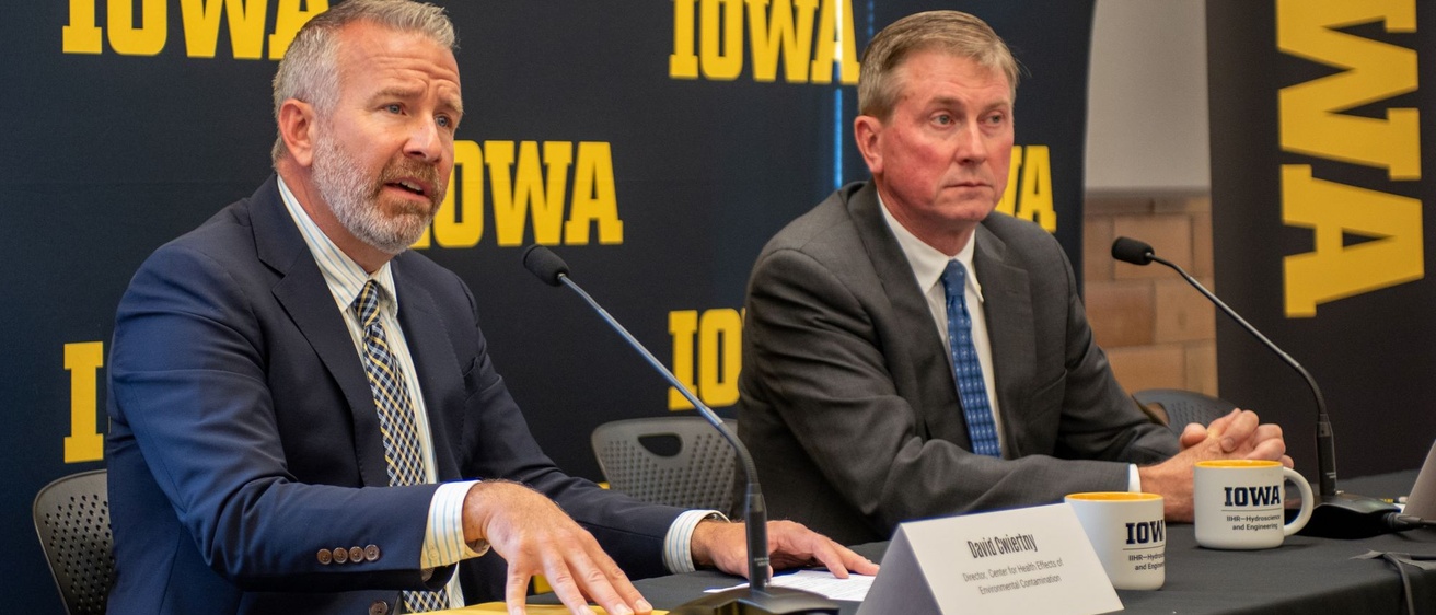 Dave Cwiertny and Larry Weber talk with the press about Iowa INSIGHT in front of a black and gold IOWA banner