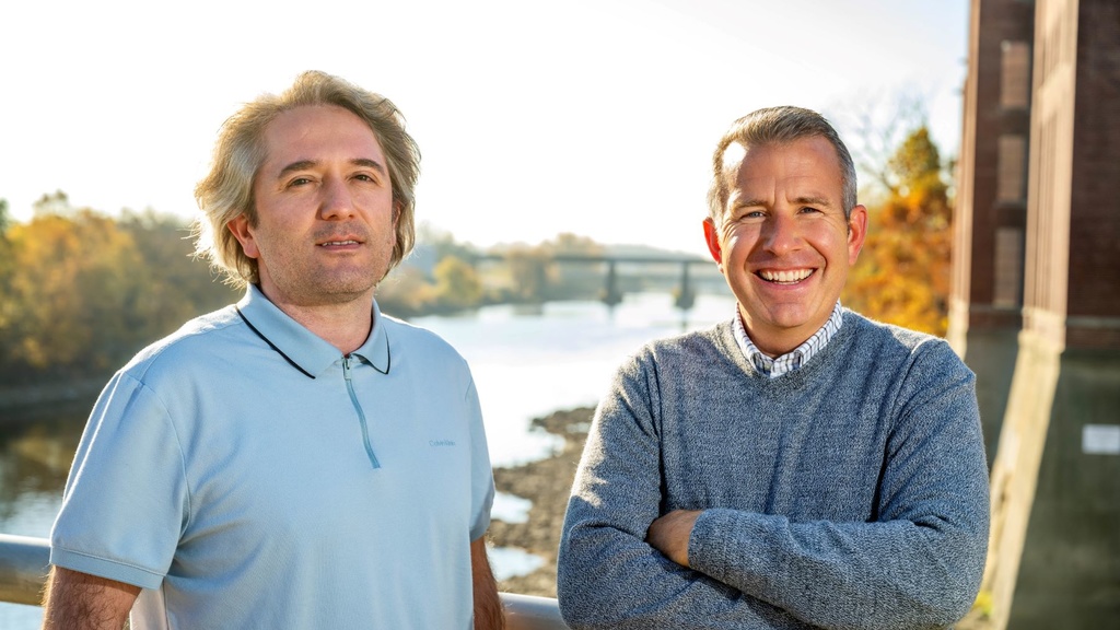 Ibrahim Demir and David Cwiertny pose for a photo next to the Iowa River
