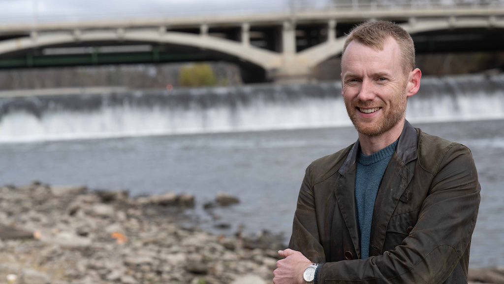 Riley Post poses next to the Iowa River