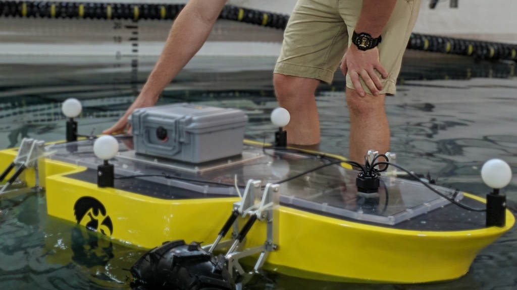 Student Andrew Arnold stands in the water with a boat model