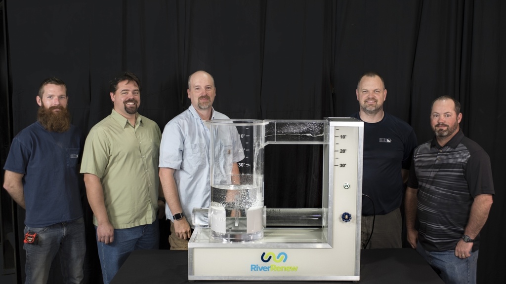 A group of men poses with a mini-model of a dropshaft