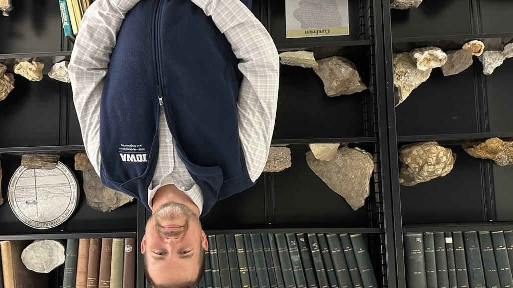Member of the Geologic Survey smiling in front of collected rocks
