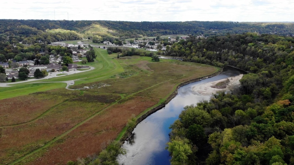 an arial of a lush green town next to a curving river