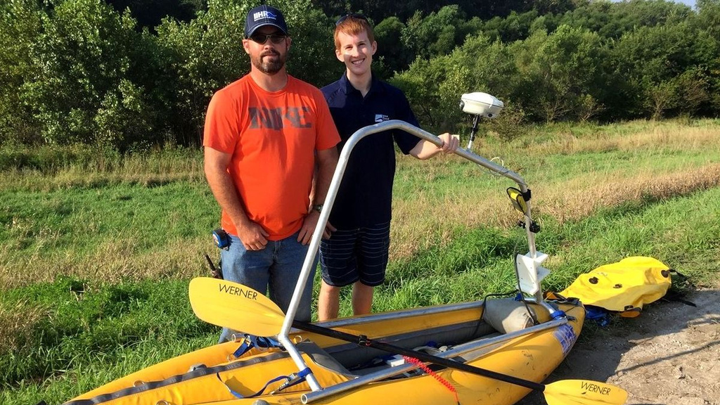 Two IIHR workers pose behind a bathymetry kayak, on a sunny day