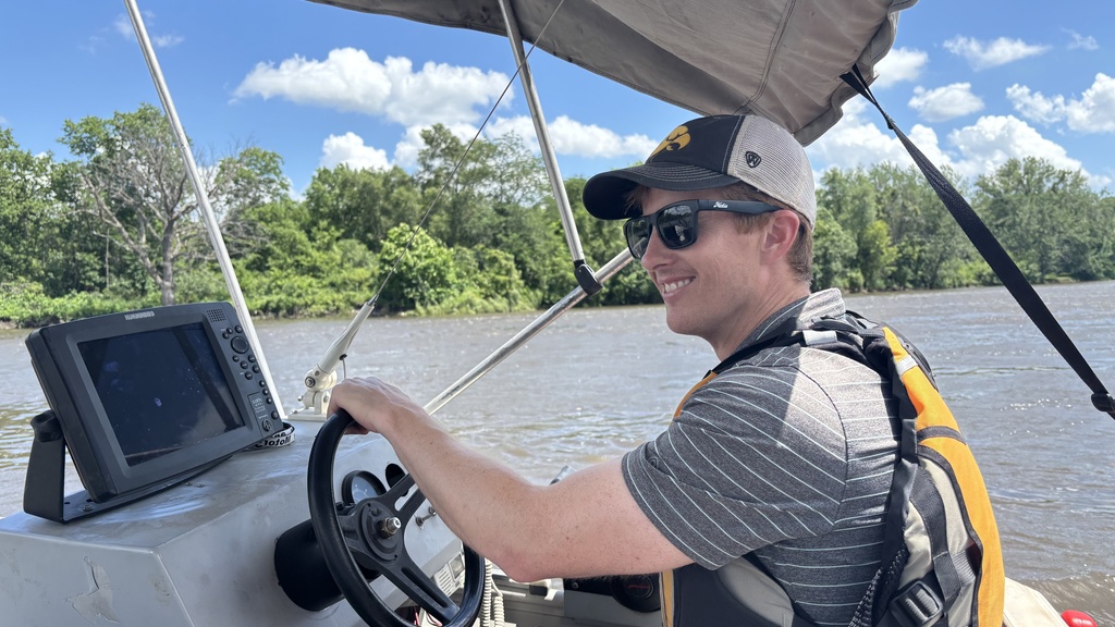 an IIHR engineer uses a boat with bathymetric technology to survey a river
