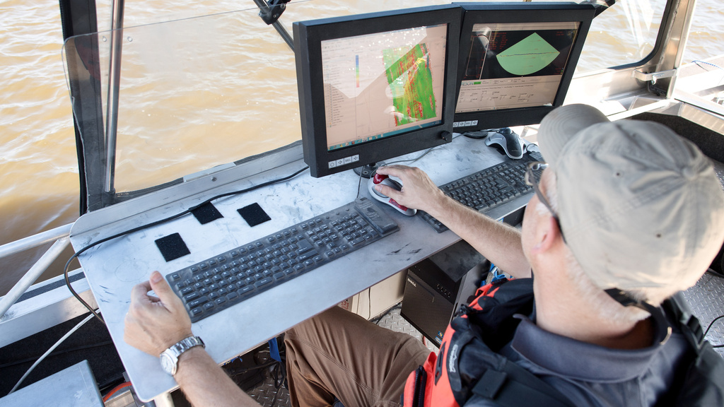 an IIHR researcher looks at the screen on a boat, checking out the bathymetry of the river