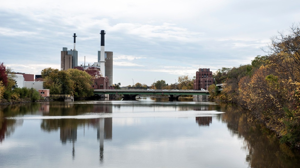 A view of the Iowa River as it flows through campus with the power plan in the background and trees along the banks