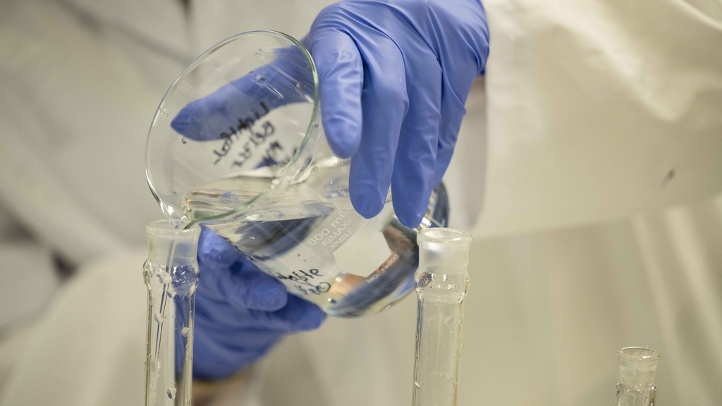 Person pouring water in a beaker in a lab