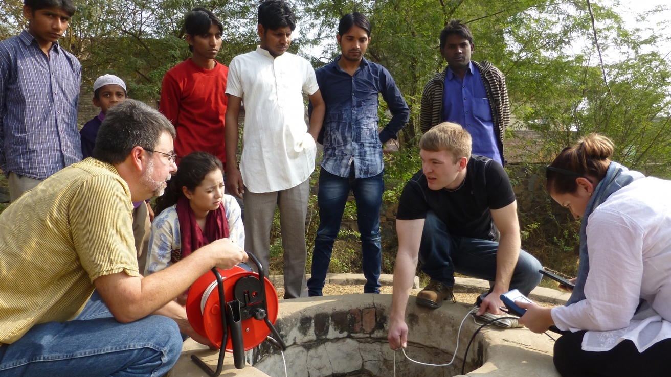 Students and faculty members conduct fieldwork with Indian colleagues at a well.