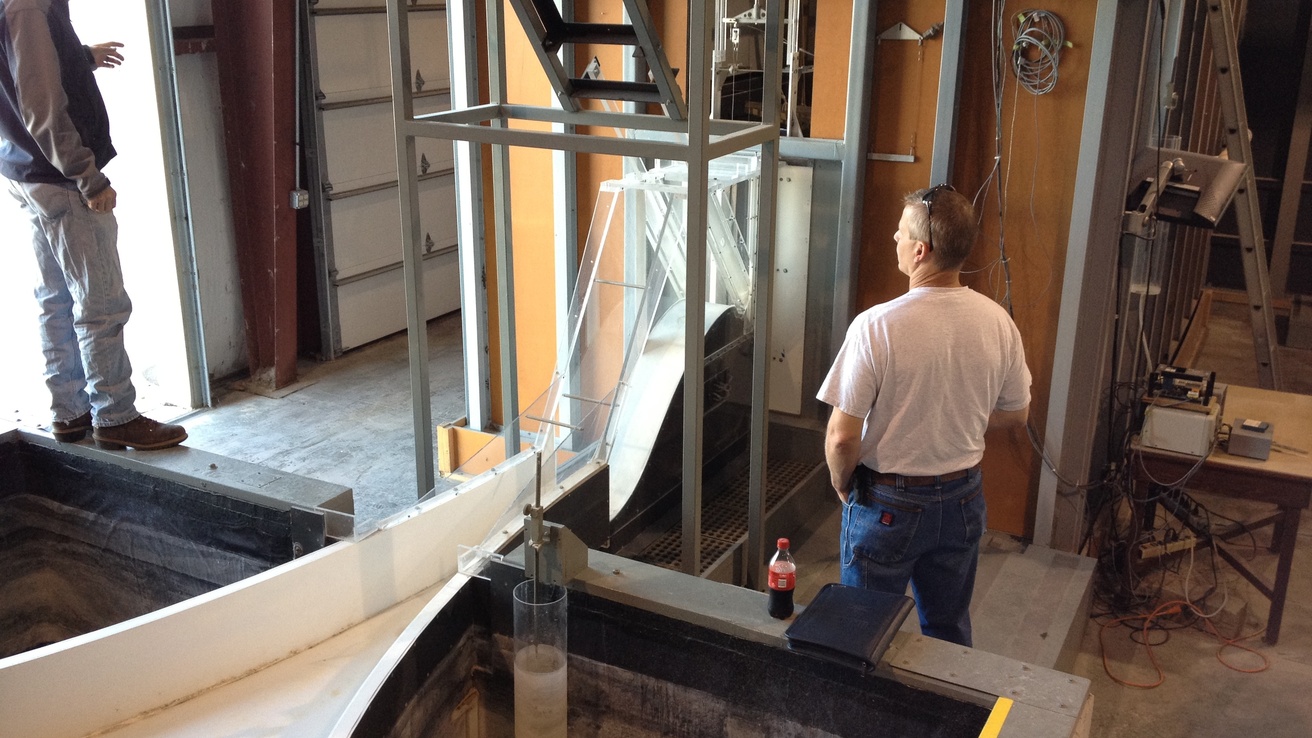 Box canyon dam model in IIHR annex, with researchers inspecting the model 